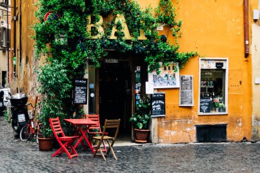 Kırmızı sandalye ve masa ile bir bar Terası. Roma'nın Trastevere bulunan. Kapı ve pencere ile turuncu cephe. Kahve içmek ve dinlenmek için yer.