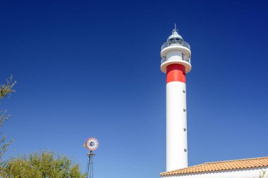 Değirmenin yanındaki deniz feneri. El Rompido, Huelva, Endülüs, İspanya 'da güneşli bir gün
