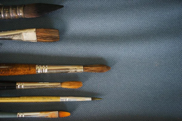 Artist's brush on the fabric, top view and close-up. Creative tools ready for use on the table. Soft focus.