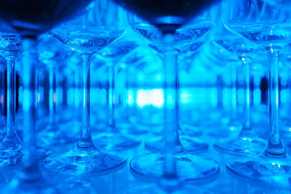 row of transparent clean wine glasses and champagne on a rack in a bar or restaurant prepared for guests of festive events.