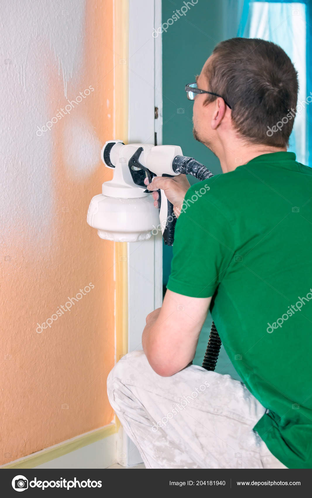 Man Painting Interior Wall House Using Spray Gun Crouching