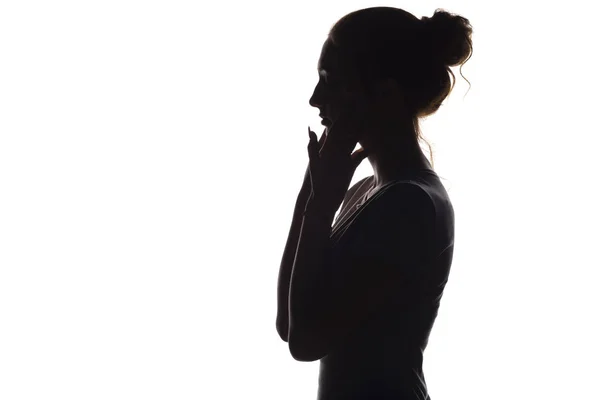 Silhouette di una giovane donna calma su uno sfondo bianco isolato, figura di ragazza con le mani sul viso — Foto Stock