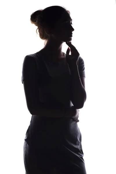 Silhouette di una giovane donna calma su uno sfondo bianco isolato, figura di ragazza magra pensosa — Foto Stock