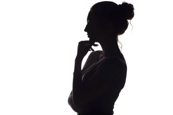 Profilo silhouette di una ragazza pensierosa con una mano sul mento, una giovane donna su uno sfondo bianco isolato — Foto Stock