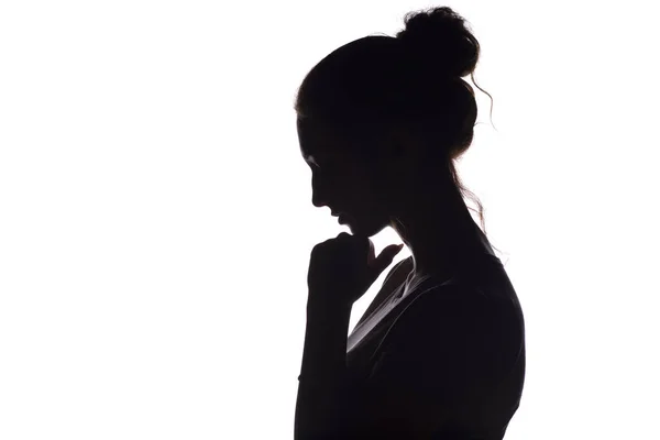 Silhouette of a thoughtful sad woman with hand near her forehead