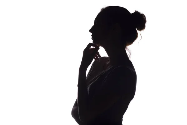 Silhueta de perfil de uma menina pensativa com uma mão no queixo, uma jovem mulher em um fundo isolado branco — Fotografia de Stock