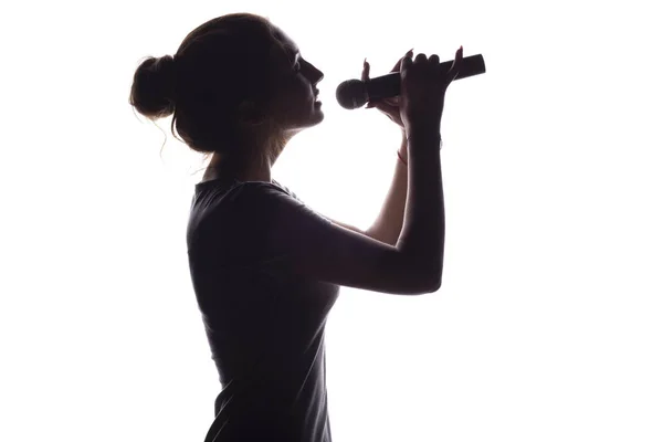 Silhouette de fille avec chant dans le microphone, profil de jeune femme visage chantant chanson lyrique sur fond blanc isolé — Photo