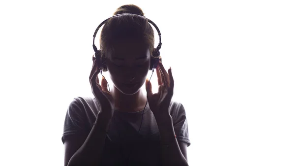 Silhouette d'une fille romantique écoutant de la musique dans des écouteurs, jeune femme se relaxant sur un fond blanc isolé, concept de passe-temps et de loisirs — Photo