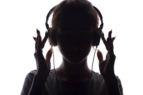 Silhueta de uma menina ouvindo música em fones de ouvido — Fotografia de Stock