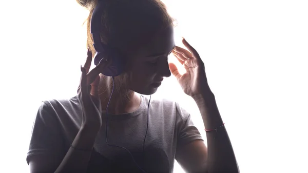 Silhouette d'une fille romantique écoutant de la musique dans des écouteurs, jeune femme se relaxant sur un fond blanc isolé, concept de passe-temps et de loisirs — Photo
