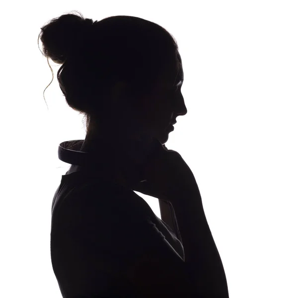 Silhouette di una ragazza con le cuffie intorno al collo, una giovane donna che ascolta musica su uno sfondo bianco isolato, concetto di hobby e relax — Foto Stock