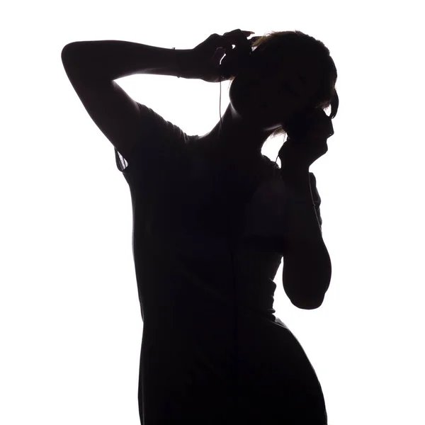 Silhouette d'une fille heureuse écoutant la chanson et se relaxant dans les écouteurs, figure de tennager passer à la musique sur un fond blanc isolé, concept de style de vie des jeunes — Photo