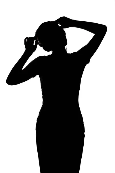 Silhueta de uma menina ouvindo música em fones de ouvido, figura de mulher relaxante em um fundo isolado branco — Fotografia de Stock