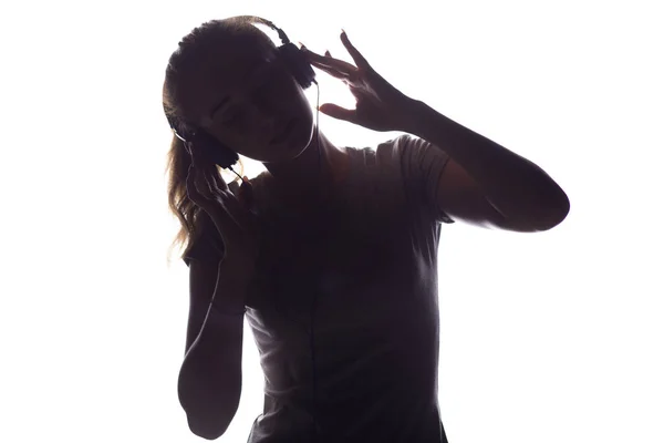 Silhueta de mulher ouvindo música em fones de ouvido — Fotografia de Stock