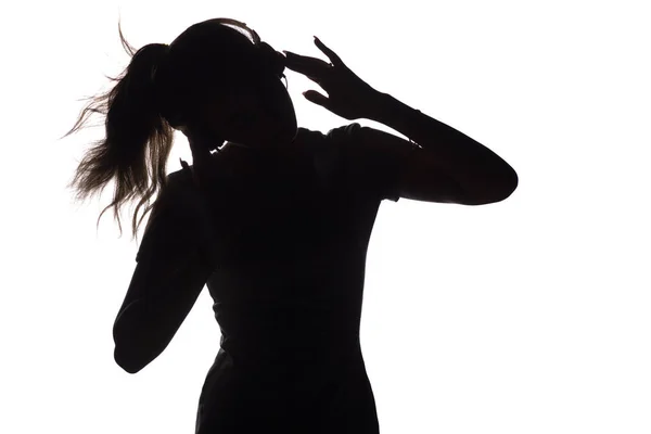 Silhouette of a girl listening to music in headphones on a white isolated background, concept of hobby and leisure — Stock Photo, Image