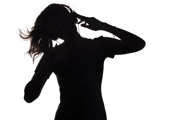 Silhouette of a girl teenager listening to music in headphones on a white isolated background, concept of hobby and leisure — Stock Photo, Image