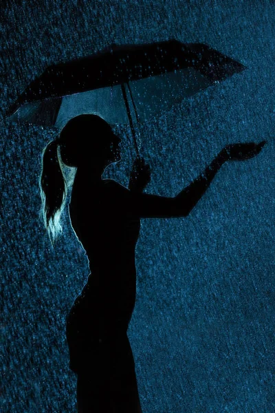 Silueta de la figura de una joven con un paraguas bajo la lluvia —  Fotos de Stock