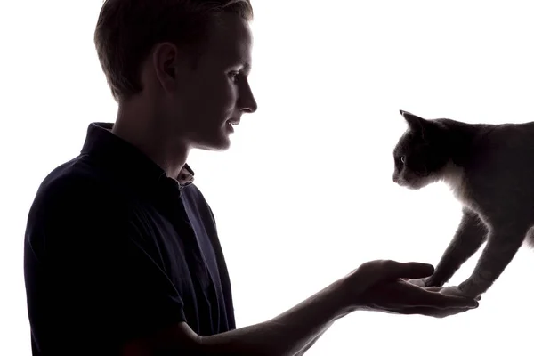 Silhouette eines Jungen mit einer Katze, Mann sieht das Haustier auf weißem, isoliertem Hintergrund — Stockfoto