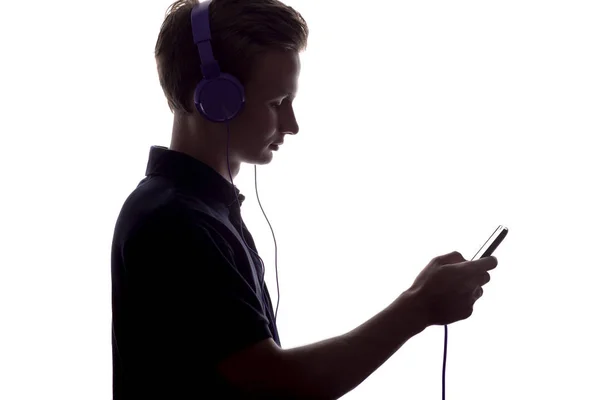 Silhueta de menino em fones de ouvido lançando playlist de música em um fundo isolado branco — Fotografia de Stock