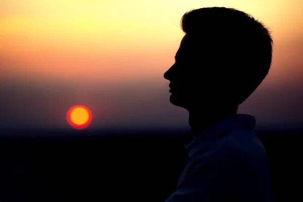 Σιλουέτα από το πρόσωπο ενός νεαρού άνδρα κατά το ηλιοβασίλεμα σε ένα χωράφι — Φωτογραφία Αρχείου