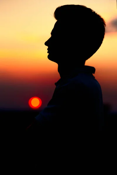 Silhouette of a sports teenager at sunset in a field, profile of a young man's face — Stock Photo, Image