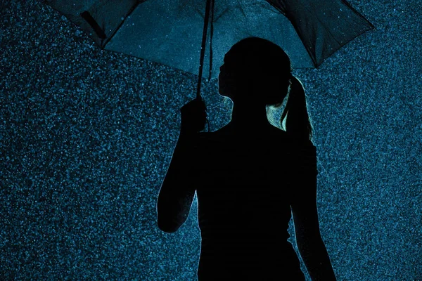 Silhueta da figura de uma jovem com um guarda-chuva na chuva, uma jovem mulher com cabelo escolhido a dedo está feliz com gotas de água, clima conceito e humor — Fotografia de Stock