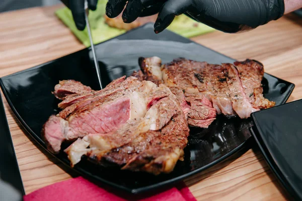 Beef steak with greens on a black plate. Steak with Basil cooked in the culinary master class