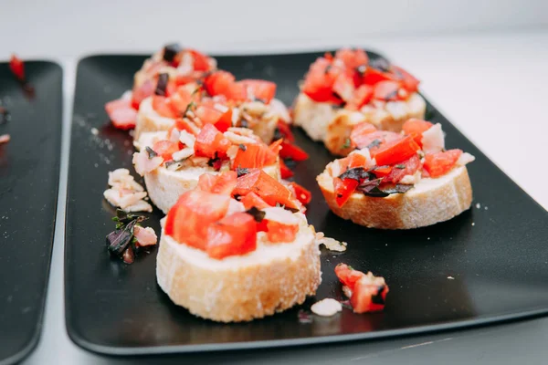 Fish and tomato sandwiches on a black plate — Stock Image Fish and tomato sandwiches on a black plate Stock Photo
