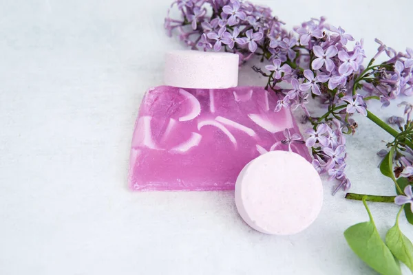 Concept of Spa-cosmetic and cosmetic procedures. Bath salt in effervescent tablets and handmade soap with lilac flowers on light concrete background. The concept of zero waste lifestyle. Space for text.