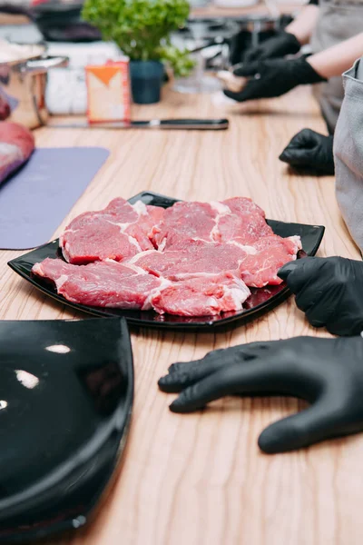 cooking steaks in a pan. cooking beef at the culinary master class. the hands of the chef in black gloves.