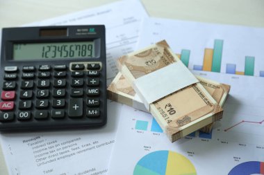 Grafik kağıt ve hesap makinesi ile Yeni Hint Para birimi notları. Ahşap arka planda izole.