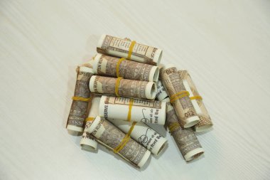 Ahşap masa üzerinde Hint 10 rupi döviz not rulo yığını.