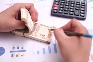 Adam el bir kalem ile yeni Hint 10 rupi notları yazıyor.