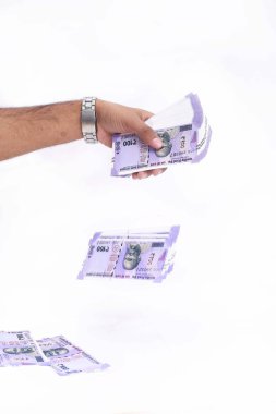 Adam eli yeni Hint parası atıyor. Beyaz arka planda yalıtılmış.