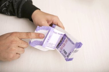 Elinde 100 rupilik Hint notları. Ahşap arka planda izole.