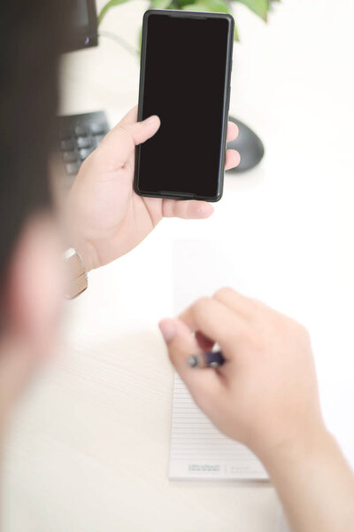 Man is using a smartphone with a pen in hand. 