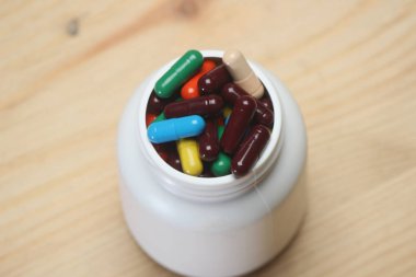 Renkli kapsülşişe ahşap arka plan üzerinde izole. Haplar herhangi bir ilaç, bitkisel veya kimyasal içerebilir. Ürün paketleme tıbbı.