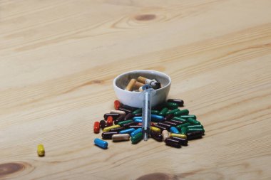 Ahşap arka plan üzerinde Ayurveda renkli ilaç, kül tablası ve enjeksiyon şırınga. 