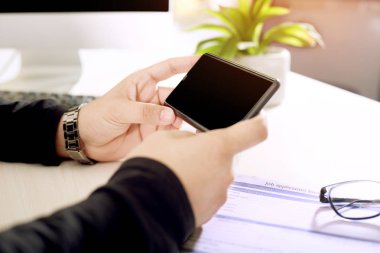Kağıt formu ve gözlük ile elinde telefon tutan adam.