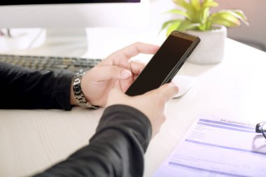 İşadamı bir masaüstü üzerinde çalışırken elle bir telefon kullanıyor.