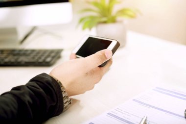 Genç bir adam bir elinde telefon tutuyor.