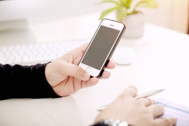 Elinde telefon ve kalem tutan adam.