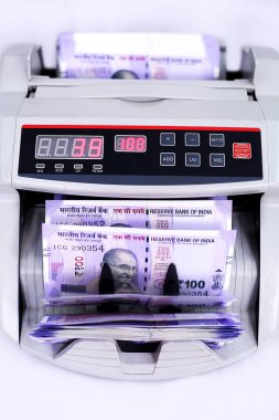 Yeni 100 rupilik banknotlarla para sayma makinesi. Beyaz arka planda yalıtılmış.