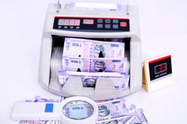 Yeni 100 rupilik banknotlar ve büyüteçile elektronik para sayacı. Beyaz arka planda yalıtılmış.
