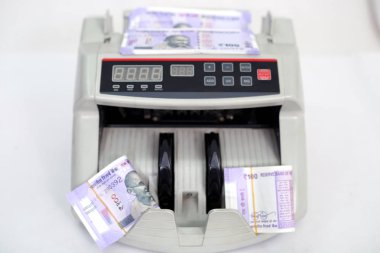 Yeni 100 rupilik banknotlarla para sayma makinesi. Beyaz arka planda yalıtılmış.