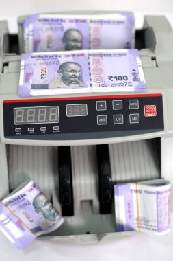Yeni 100 rupilik banknotlarla elektronik para sayacı. Beyaz arka planda yalıtılmış.