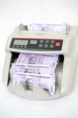 Yeni Hint 100 rupi banknotları ile elektronik para sayacı. Beyaz arka planda yalıtılmış.