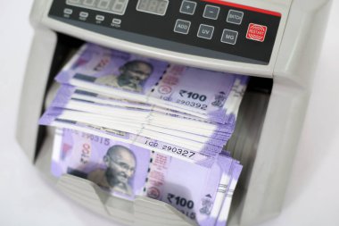 Otomatik bir makinede yeni Hint para birimi sayma. Beyaz arka planda yalıtılmış.