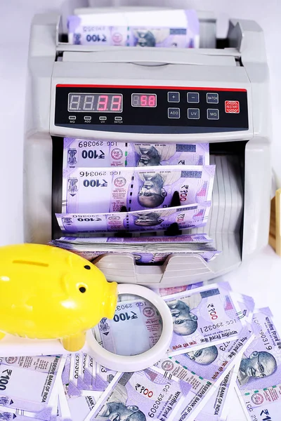 Yeni Hint para birimi, nakit sayma makinesi, büyüteç ve sarı kumbara resmi. Beyaz arka planda yalıtılmış.