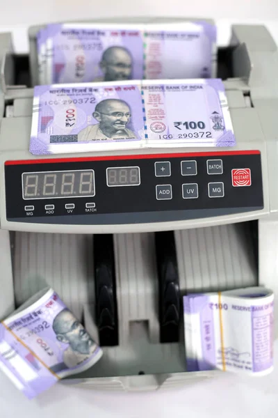 Yeni 100 rupilik banknotlarla elektronik para sayacı. Beyaz arka planda yalıtılmış.
